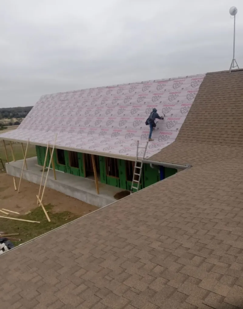Worker preparing underlayment for a metal roof installation in Fairmount
